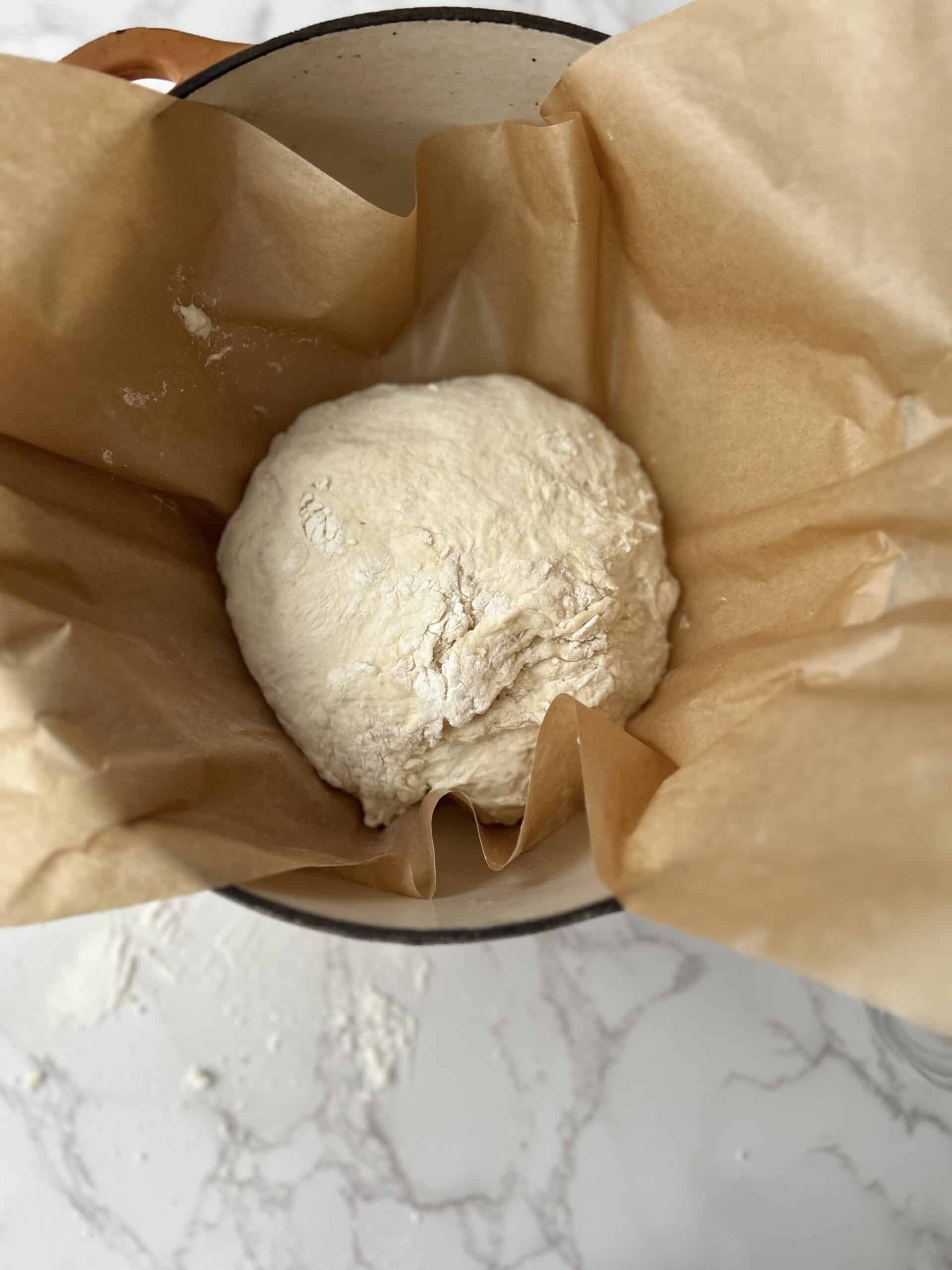 Shaped dough placed on the hot dutch oven (with parchment paper) ready to be baked.