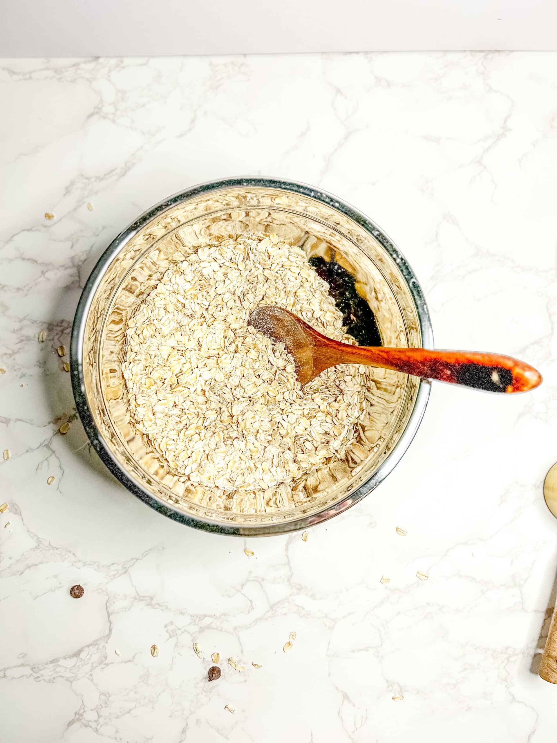 A mixing bowl and a wooden spoon with the dry ingredients mixed