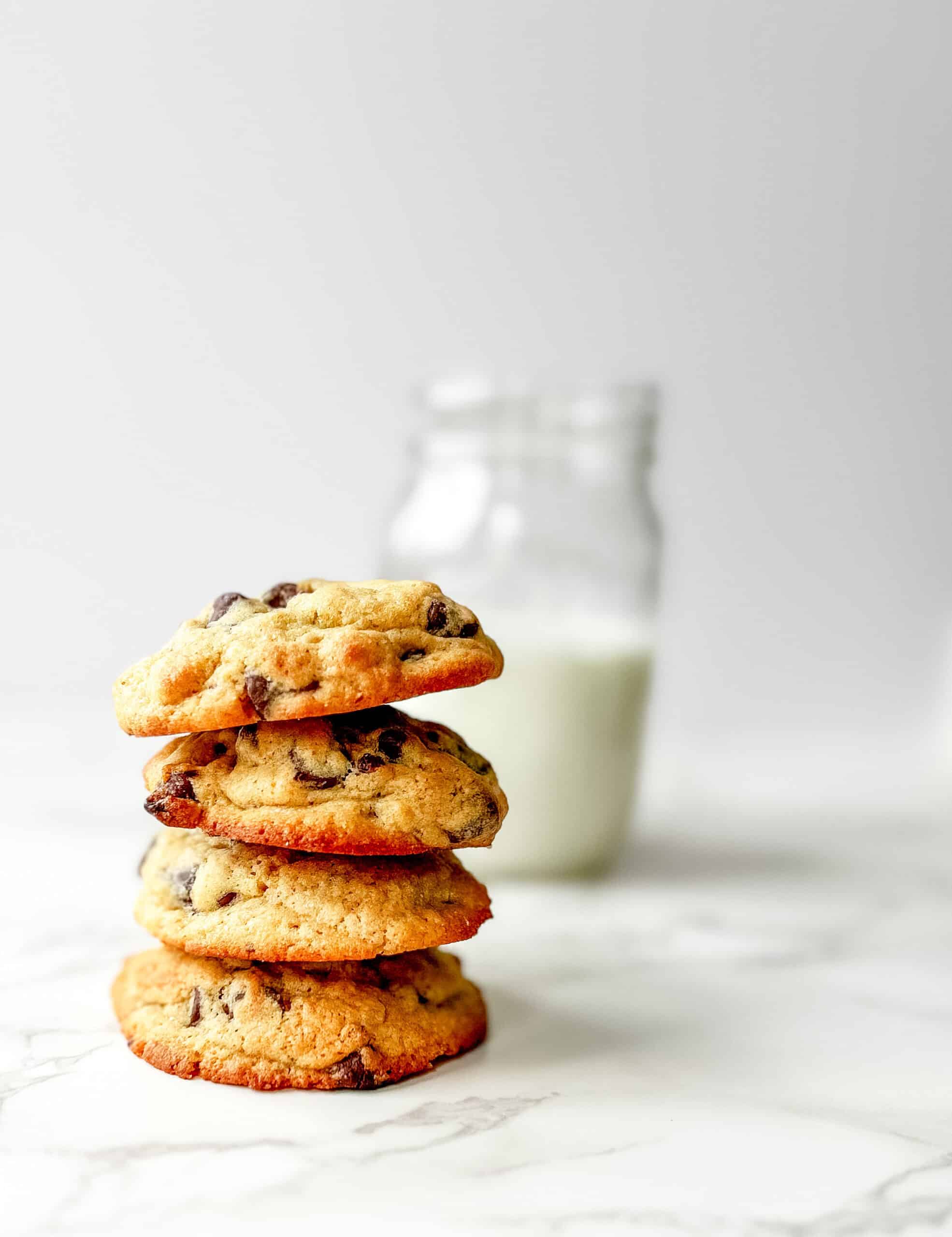 4 fresh milled flour sourdough cookies stack on top of eachother vertically with a mason jar of milk in the background