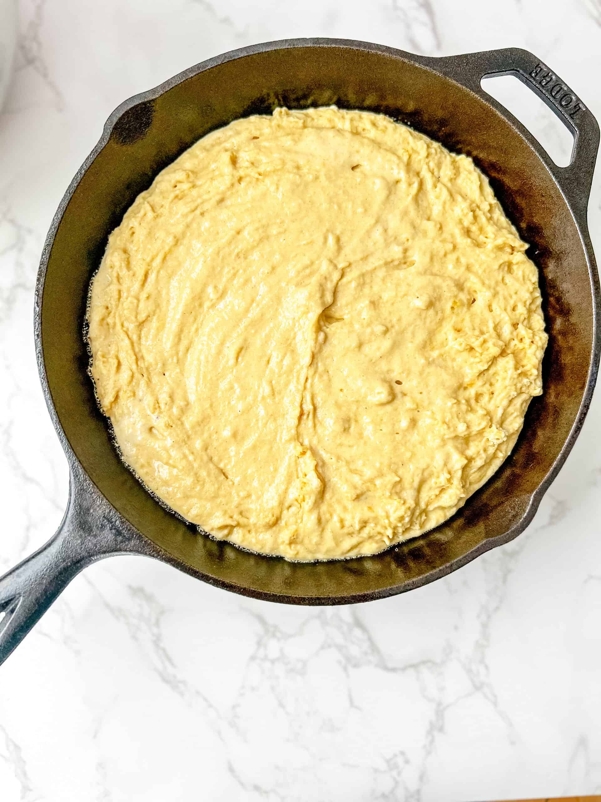 Cornbread batter poured into the lodge cast iron, ready to bake