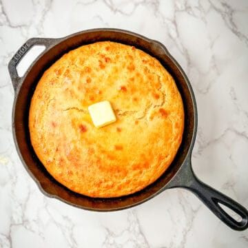 Fresh Milled Flour Cornbread with a pad of butter in a cast iron skillet